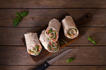 Fototapeta na wymiar Salmon and cream cheese wraps. Rolls with smoked salmon. Homemade tasty burrito