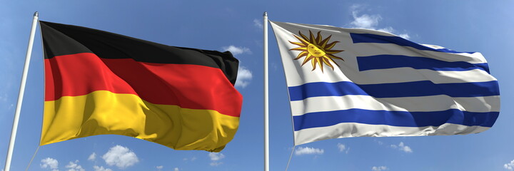 Flying flags of Germany and Uruguay on high flagpoles. 3d rendering