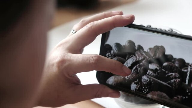 woman taking picture macro close up roasted coffee beans with smartphone 