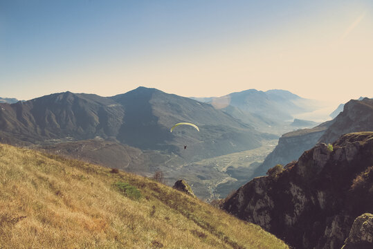 paraglider flying in the mountains with autumnal sunet light