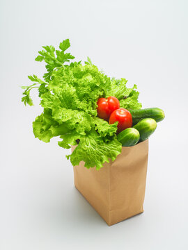 Healthy food. Fresh herbs and vegetables in kraft paper bag on white background