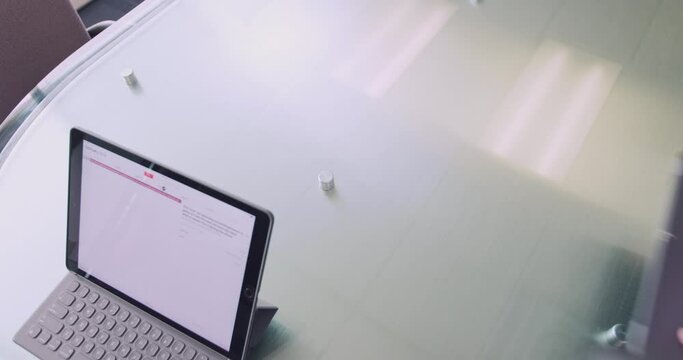 Overhead shot of three people entering frame and picking up their computer and tablet