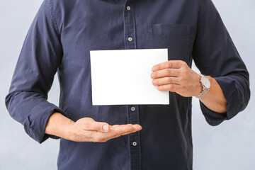 Man with blank paper sheet on white background