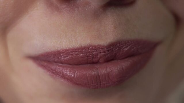 Woman is smiling widely and moving her mouth making different gestures. Closeup of caucasian lady's face part expressing emotions. Theme of people and their face that can tell much about person.