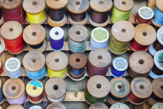 An empty peg with colored sewing spools of threads on a rack