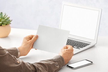 Man with blank paper sheet at table in office