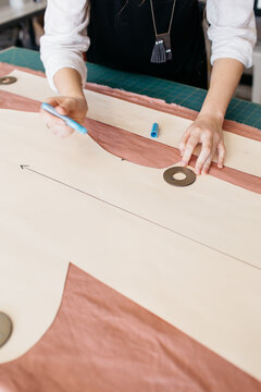 hands tracing a pattern on pink linen fabric