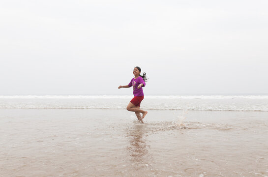 Teenage gilr running and making fun in a sea beach