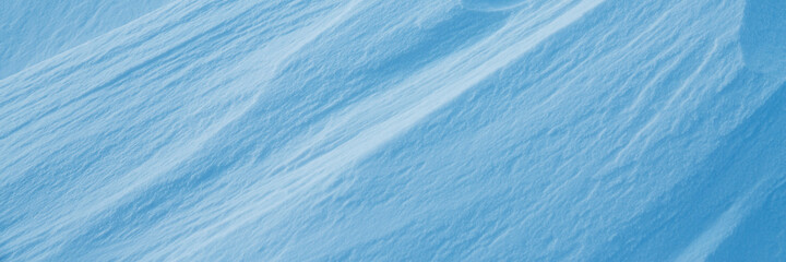 Snow texture. Wind sculpted patterns on snow surface. Wind in the tundra and in the mountains on the surface of the snow sculpts patterns and ridges. Arctic, Polar region. Winter panoramic background.