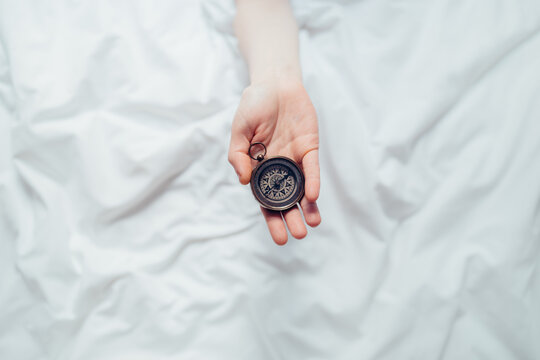hand holding a compass over white sheets