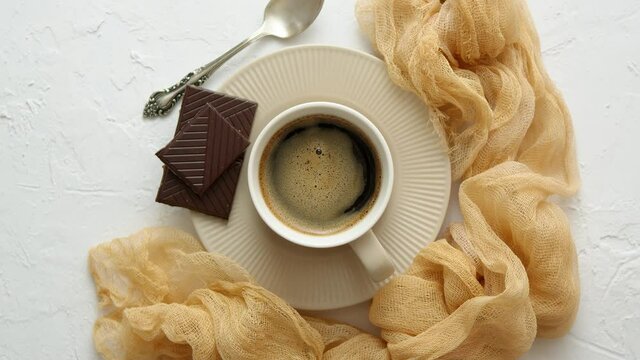 Black Coffee cup with dark chocolate on side. Placed on white kitchen table