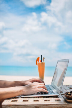 Man using laptop and phone on beach
