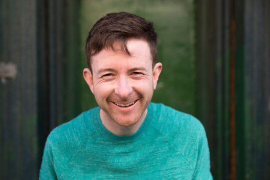 Redhead man smiling in a green doorway