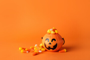 Basket with tasty candy corns for Halloween on color background