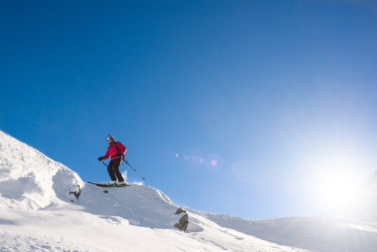 Male skier jumping off a cliff on a bright sunny day