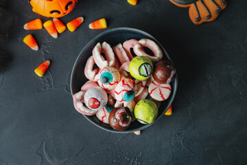 Bowl with tasty treats for Halloween on dark background