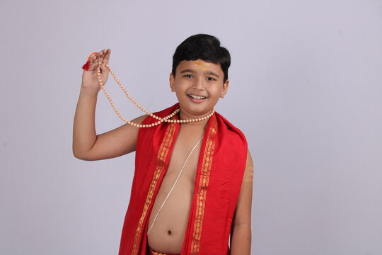 Indian boy in ethnic wear showing off his rosary or string of prayer beads with smile.