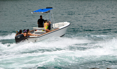 Obraz premiumFive women and one man enjoying a high speed cruise in an open sport fishing boat.