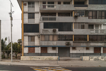 Manta, Ecuador - December 2, 2008: Gray cement facade of apartment building in street with AC...