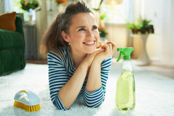 smiling woman with cleaning agent and brush laying on carpet