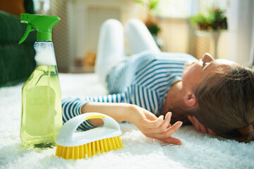 woman with cleaning agent and brush laying on carpet