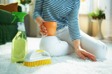 female with cleaning agent and brush touching carpet with cup