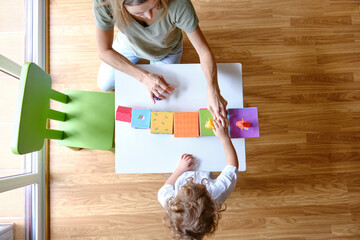 Mother playing with her child at home, top view