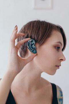 Unusual portrait of a beautiful female with a clay ear in her hand