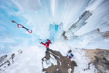 Female ice climber ascending on frozen watrefall