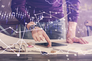 Double exposure of man's hands holding and using a digital device and forex graph drawing. Financial market concept.