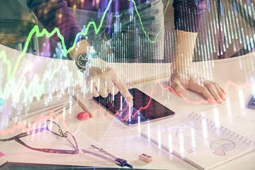 Double exposure of man's hands holding and using a digital device and forex graph drawing. Financial market concept.