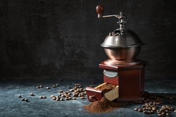 Wooden vintage coffee grinder, roasted beans and ground coffee on a dark rustic background with copy space, selected focus - obrazy, fototapety, plakaty