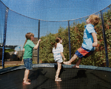 Kids Bouncing on an Enclosed Backyard Trampoline