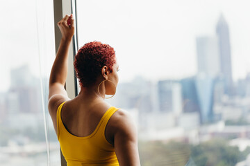 Woman looking out window thinking and reflecting at home