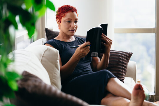 Black woman reading a book at home during pandemic