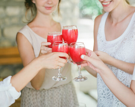 Cheerful women clanging juice glasses