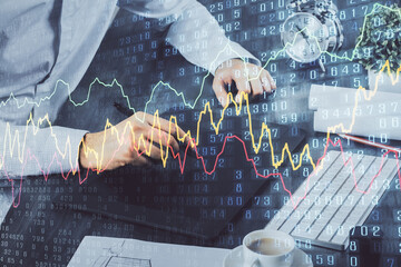 Double exposure of man's hands holding and using a phone and financial graph drawing. Analysis concept.