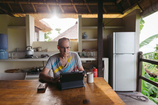 Mature man in his 60's working and traveling with tablet in trop