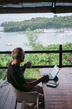 Mature man in his 60's working and traveling with tablet in trop