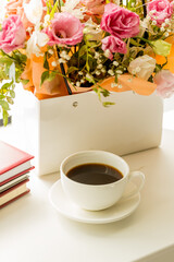 light romance background. coffee cup with notepad and flowers bouquet on a window sill. love and romance concept