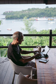 Mature man in his 60's working and traveling with tablet in trop