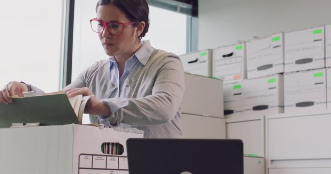 A woman sorts through and logs boxes of files on a tablet.