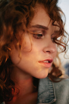 Profile portrait of young curly woman with flares on her face