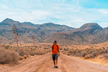 A young man walking along a desert path in the natural park of Cabo de Gata, Nijar, Andalusia. Spain, Mediterranean Sea