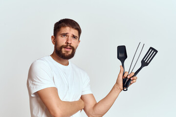 A man with kitchen appliances in the hands of their white T-shirt on a light background cropped view