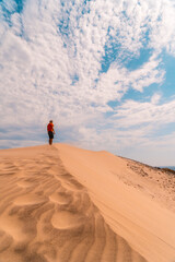 A man with a red shirt and a turban on his head, walking in the desert of the dune of Playa de Mónsul in the natural park of Cabo de Gata, Nijar, Andalucia. Spain, Mediterranean Sea