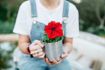 Woman with red flower in metallic pot.