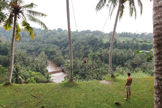 Brave young girl on hgh swing over tropical valley