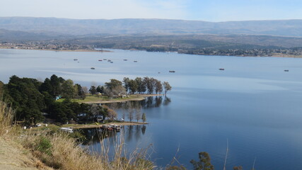 Vista de un lago artificial, con monta&ntilde;as en el fondo.