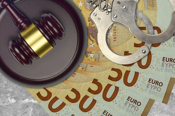 50 euro bills and judge hammer with police handcuffs on court desk. Concept of judicial trial or...